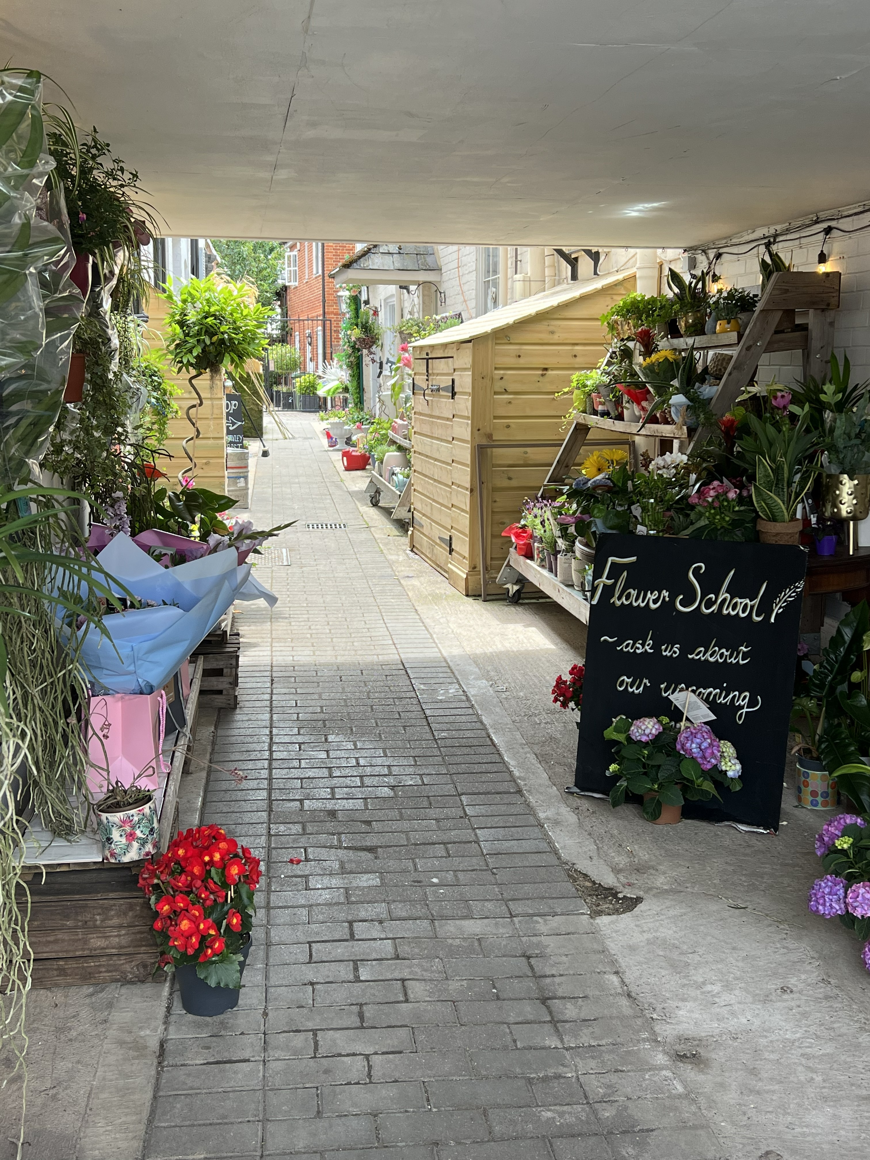 The flower shop in the covered alleyway leading to Barlows Mews, lit by summer sun