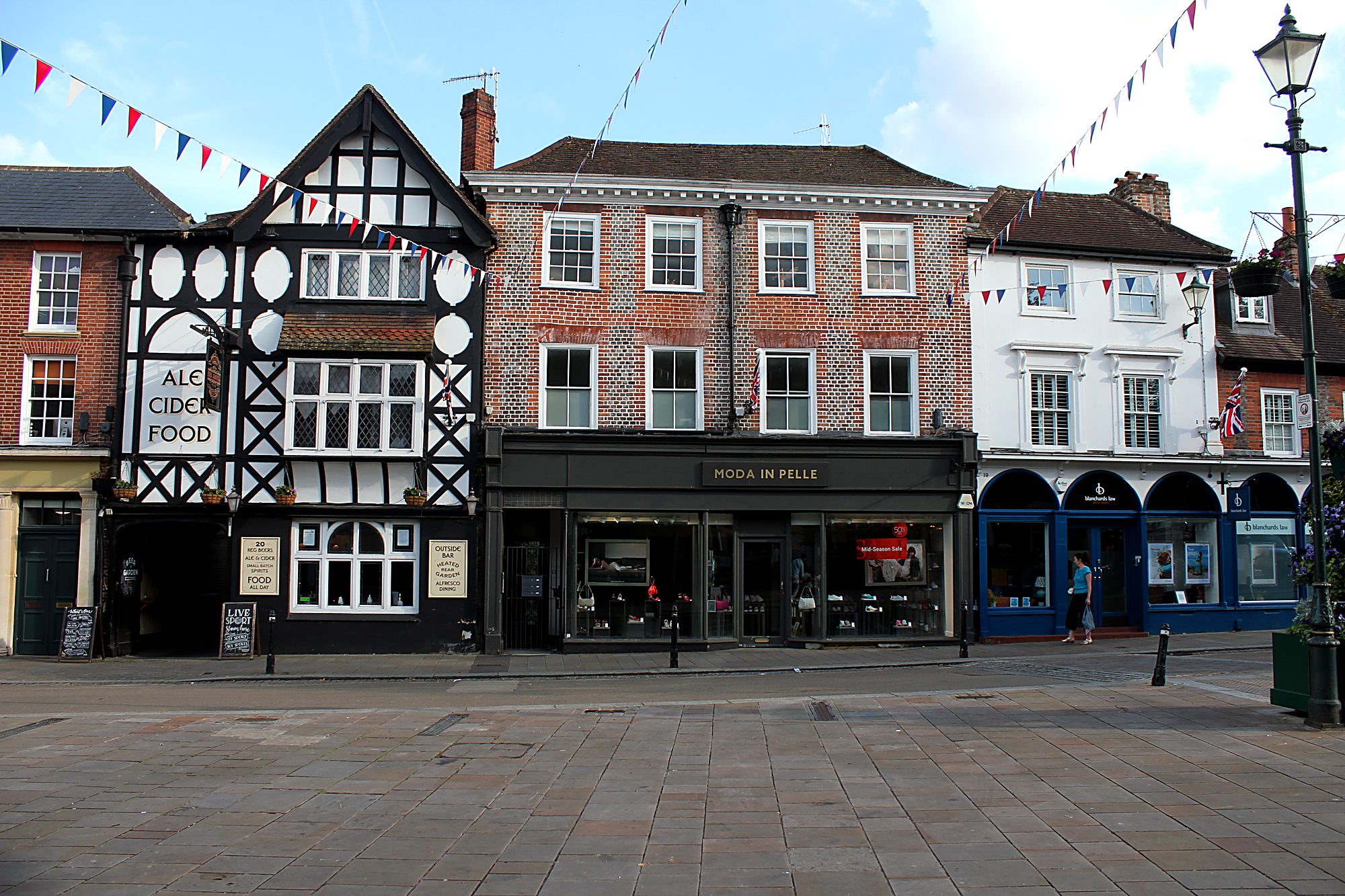 Market Place streetscape in central Henley — Tudor and brick buildings with summer bunting